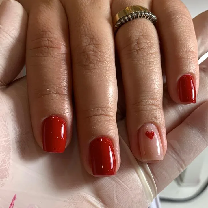 Unhas quadradas curtas em vermelho com um coração delicado