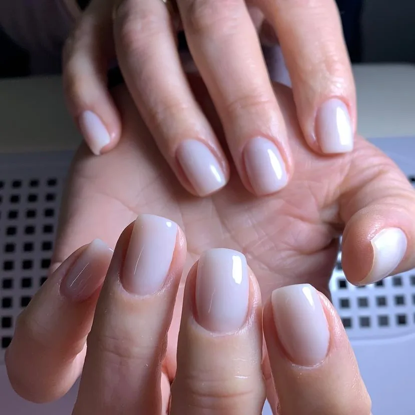 Duas mãos com unhas quadradas em branco leitoso